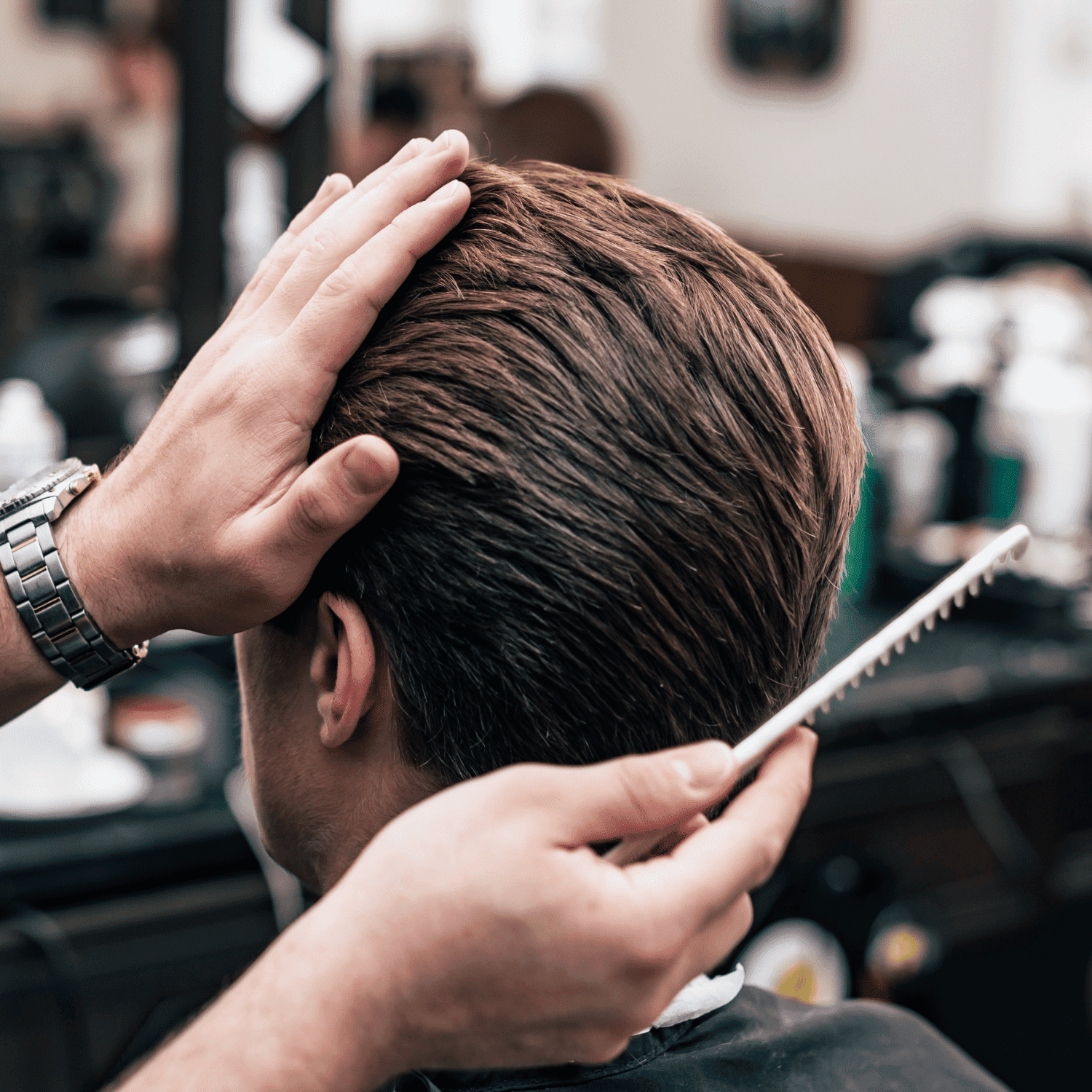 Barber styling a man's hair with a comb in a salon.