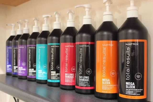 Shelf displaying various Matrix Total Results hair care products in colorful bottles.